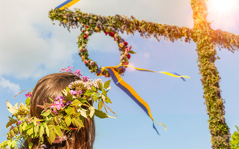 Girl with floral crown by a Midsummer maypole