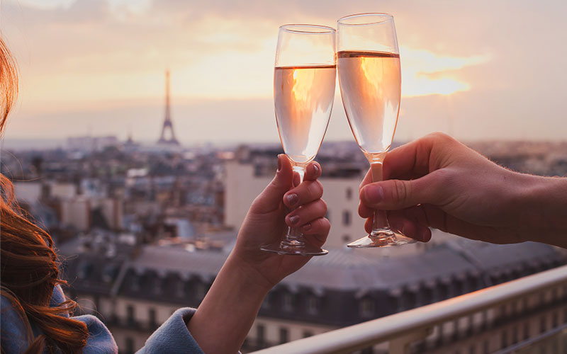 Two people celebrating with champagne in front of the Eiffel Tower